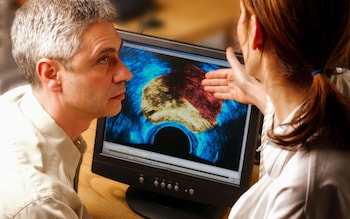 A posed photo representing a doctor examining a cancer scan