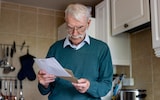 Male pensioner at home reading a letter he got in his mail